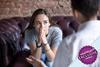 Young woman sat on couch looking pensive whilst talking to someone