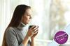 Woman holding a cup of tea staring out of a window