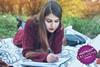 Young woman lying on a blanket in a park writing