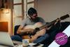 A man playing guitar in his living room
