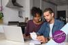 Couple sat at kitchen table in front of laptop checking receipts