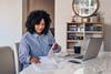 Woman sat in front of laptop sorting paperwork