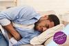 Man lying on bed clutching stomach in pain