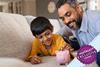 Father and son playing with piggy bank on sofa