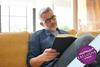 Man sat on sofa reading a book