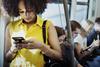 Young woman standing in a bus looking at her phone