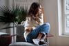 woman curled up on a chair biting her nails staring out of a window