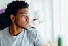 Young man looking despondent staring out a window