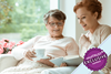 Young woman reading to an older lady smiling