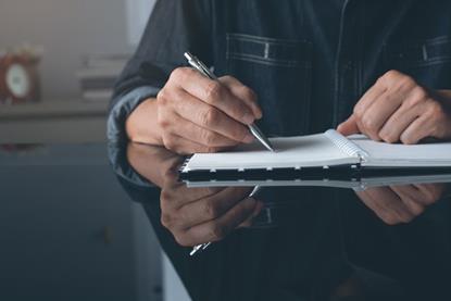 Someone making notes in a notepad at a table