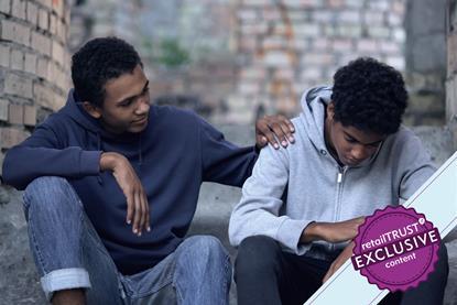 Young man sat with a friend with a comforting hand on his shoulder