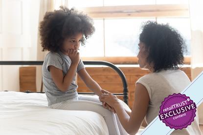 Parent explaining something to a child sat on a bed