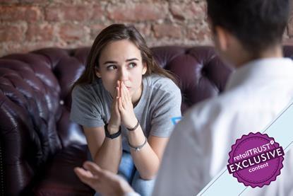 Young woman sat on couch looking pensive whilst talking to someone
