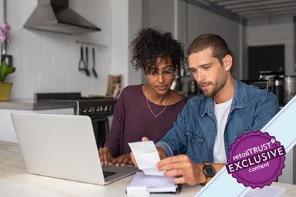 Couple sat at kitchen table in front of laptop checking receipts