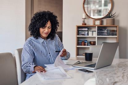 Woman sat in front of laptop sorting paperwork