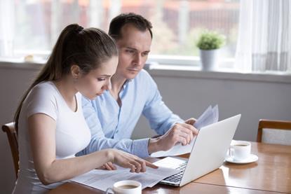 Couple sat at a table looking at a laptop making notes