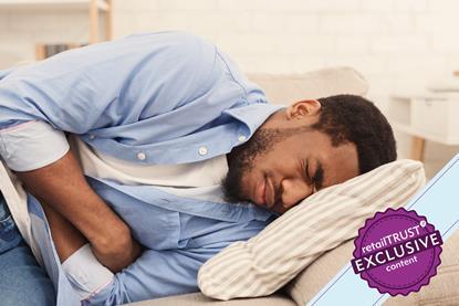 Man lying on bed clutching stomach in pain