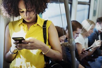 Young woman standing in a bus looking at her phone