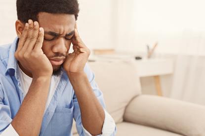 Man sat on sofa rubbing his temples
