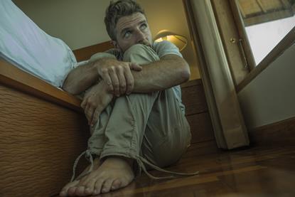 Man looking scared sat on bedroom floor