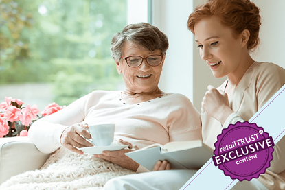 Young woman reading to an older lady smiling