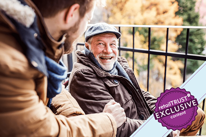 Younger and older man sitting on a park bench laughing